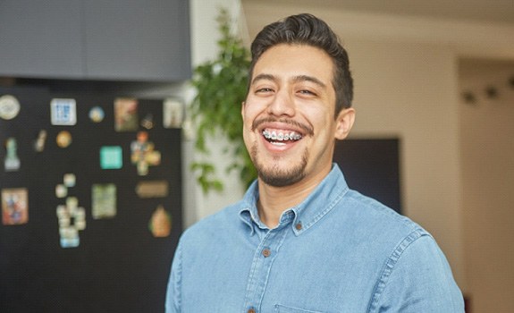 Man in denim shirt smiling in kitchen at home