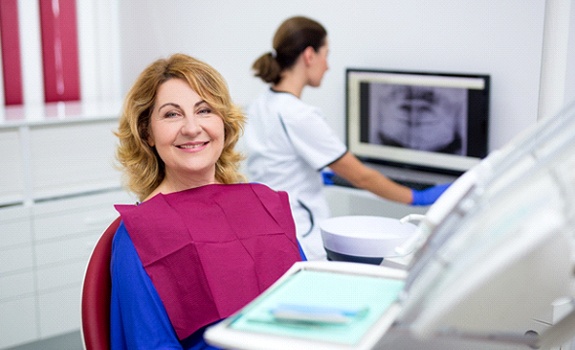 Middle-aged woman smiling while sitting in dental chair