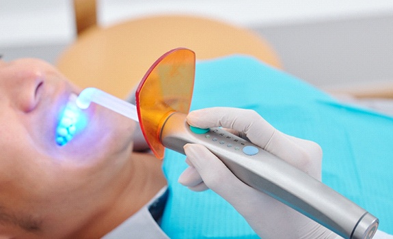 A dentist in Lakewood using a curing light to harden composite resin used on a patient