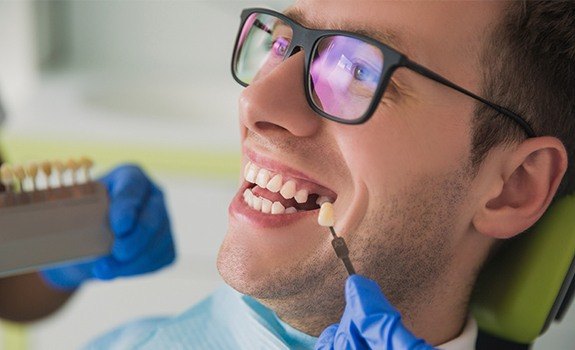 Man with missing teeth looking at tooth replacement color options