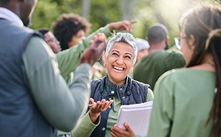 Smiling woman talking to volunteers outside