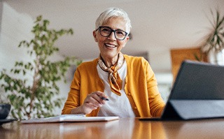 Woman smiling while working on tablet at home