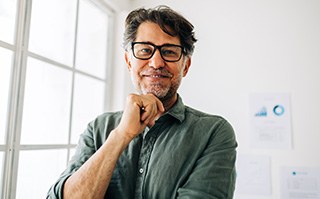 Man with black glasses smiling in office