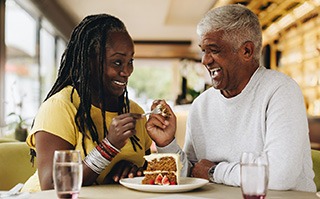 Couple smiling while splitting dessert at restaurant