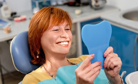 Patient smiling at small mirror