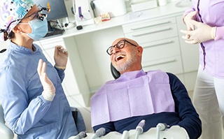 Happy patient laughing with his dental team