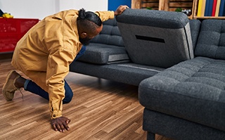 Man looking for something under couch cushion