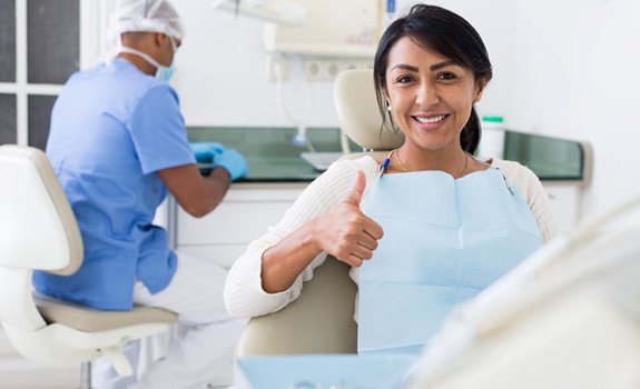 Happy female dental patient making thumbs-up gesture